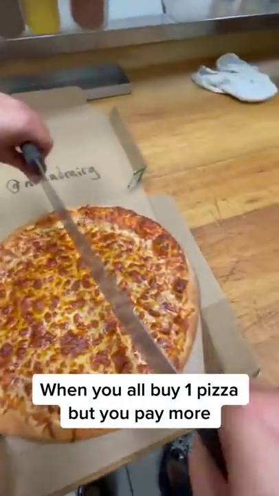 當圓形的大Pizza被放上工作台後，就有人在Pizza上快切了兩刀